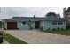 Charming light-blue single-story home with a paved driveway, wood garage door, and landscaped yard at 861 180Th E Ave, Redington Shores, FL 33708