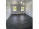 A bright bedroom with two windows offering natural light and dark gray laminate flooring at 8708 Cobbler Pl, Tampa, FL 33615