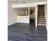 A view of the living room and kitchen area, featuring gray wood floors and staircase at 8708 Cobbler Pl, Tampa, FL 33615