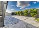 Backyard featuring a gray storage building, hardscape patio, rock landscaping, and a perimeter of palms at 8812 Parsons Hill Blvd, Wesley Chapel, FL 33545