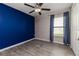 Bedroom featuring a gray wood-look floor, bright blue accent wall and a ceiling fan at 8812 Parsons Hill Blvd, Wesley Chapel, FL 33545