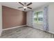 Bright bedroom with gray wood-look flooring, fan, and natural light from a window with decorative curtains at 8812 Parsons Hill Blvd, Wesley Chapel, FL 33545