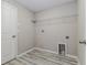 Neutral laundry room area with gray wood-look flooring, wire shelving, and utility connections at 8812 Parsons Hill Blvd, Wesley Chapel, FL 33545