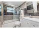 Well-lit bathroom featuring marble-style tile, a modern vanity, and a bathtub with sliding glass doors at 8918 Carmen Ln, Port Richey, FL 34668