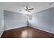 An empty bedroom with hardwood floors, a ceiling fan, and windows that bring in natural light at 8918 Carmen Ln, Port Richey, FL 34668