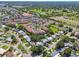 Wide aerial shot showcasing a neighborhood with condos, pools, mature trees, and nearby golf course views at 94 Nicholas Dr, Dunedin, FL 34698