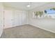 Carpeted bedroom featuring a ceiling fan, closet, and a window letting in natural light at 94 Nicholas Dr, Dunedin, FL 34698