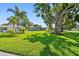 The home has a neatly manicured lawn, mature trees, and lush landscaping adding to its curb appeal at 94 Nicholas Dr, Dunedin, FL 34698