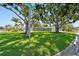 Beautifully landscaped front yard with lush green grass and mature trees, offering curb appeal at 94 Nicholas Dr, Dunedin, FL 34698
