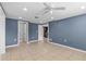 This bedroom features tile flooring, ceiling fan, and neutral blue paint at 9915 Aetna Ln, Port Richey, FL 34668