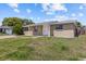Tan single-story home with white trim, front yard, and overcast sky at 9915 Aetna Ln, Port Richey, FL 34668