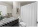 Clean bathroom featuring a sink with granite countertop, toilet, and shower with white curtain at 10197 Meadow Wren Ave, Weeki Wachee, FL 34613