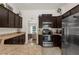 Modern kitchen with dark cabinets, stainless steel appliances, and stone countertops at 10197 Meadow Wren Ave, Weeki Wachee, FL 34613