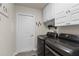 Bright laundry room features modern washer and dryer, white cabinets, and gray tile floors at 10197 Meadow Wren Ave, Weeki Wachee, FL 34613