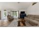 Cozy living room with comfortable seating, wood floors, a mounted TV, and view to exterior at 10197 Meadow Wren Ave, Weeki Wachee, FL 34613