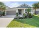 Charming single-story home with a well-manicured front yard, landscaped with palm trees and lush green grass at 10464 Tranquil Meadow Loop, Riverview, FL 33569