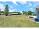 Large, grassy backyard with a view of a storage building and surrounded by trees on a sunny day at 10722 Sumner Rd, Wimauma, FL 33598
