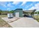 Green barn with covered outdoor storage area, garage door, and partial view of a trailer at 10722 Sumner Rd, Wimauma, FL 33598