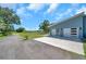 Side view of a blue home featuring two white garage doors and an adjacent lawn with mature trees at 10722 Sumner Rd, Wimauma, FL 33598