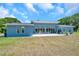 Rear exterior of a modern home with large sliding glass doors leading to an outdoor patio at 10722 Sumner Rd, Wimauma, FL 33598