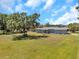 Single-story home with a grey exterior, well-manicured lawn, and mature trees at 10722 Sumner Rd, Wimauma, FL 33598