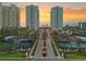 Stunning aerial view of beachfront condo complex with lush landscaping, tennis courts, and ocean views at sunset at 1180 Gulf Blvd # 402, Clearwater Beach, FL 33767