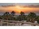 Balcony view overlooking palm trees and a sandy beach as the sun sets over the ocean at 1180 Gulf Blvd # 402, Clearwater Beach, FL 33767