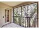 Screened patio with view of trees and black metal railing with tiled floor and door to unit at 11800 Park Blvd # 208, Seminole, FL 33772