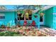 Inviting front porch featuring colorful chairs surrounded by lush plants, stone trim, and brick pavers at 12176 Croft Dr, Largo, FL 33774