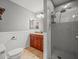 Bathroom featuring a tiled walk-in shower, wooden cabinets, wainscoting, and neutral wall paint at 14103 Stonebrook Ct, Tampa, FL 33624