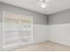 Bright bedroom featuring wainscoting, a large window, a ceiling fan, and neutral colored carpet flooring at 14103 Stonebrook Ct, Tampa, FL 33624