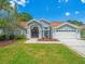 Charming single-story home with manicured lawn, double-door entry, and two-car garage, all under a bright blue sky at 14103 Stonebrook Ct, Tampa, FL 33624