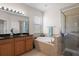 A bright primary bathroom boasts double vanity, soaking tub, and enclosed glass shower for a spa-like experience at 1517 Yale Castle Ct, Ruskin, FL 33570