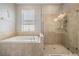 Bright bathroom featuring a soaking tub with tile surround and glass-enclosed shower stall at 1524 Rhodeswell Ln, Dover, FL 33527