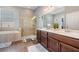Main bathroom featuring a double vanity, soaking tub, walk-in shower, neutral tile, and decor at 1524 Rhodeswell Ln, Dover, FL 33527