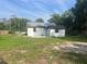 View of a house's backyard with green grass, featuring a semi-circle bricked firepit in the grass at 18127 Us Highway 41, Spring Hill, FL 34610