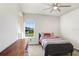Bright bedroom featuring a ceiling fan and a large window with a view of the green lawn at 18824 Birchwood Groves Dr, Lutz, FL 33558