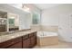 Bright bathroom with double vanity, soaking tub, and tiled floors at 19711 Wellington Manor Blvd, Lutz, FL 33549