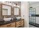 Stylish bathroom featuring a double vanity, stone accent wall, and walk-in shower with glass door at 19711 Wellington Manor Blvd, Lutz, FL 33549