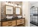 Modern bathroom featuring a double vanity, stone accent wall, and walk-in shower with glass door at 19711 Wellington Manor Blvd, Lutz, FL 33549