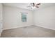 A vacant bedroom featuring neutral carpet, a ceiling fan, and natural light from a window at 19711 Wellington Manor Blvd, Lutz, FL 33549