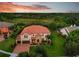 Beautiful sunset aerial view of home with tile roof, lush landscaping, and attached two-car garage at 19711 Wellington Manor Blvd, Lutz, FL 33549