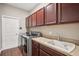 This laundry room features a stainless steel washer and dryer with dark cabinetry and laminate countertops at 19711 Wellington Manor Blvd, Lutz, FL 33549