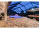 Evening shot of the screened-in pool featuring a rock waterfall, seating area, and umbrella at 19711 Wellington Manor Blvd, Lutz, FL 33549