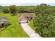 Aerial view of a charming home featuring a mature tree, driveway, and well-manicured lawn at 206 Forest Wood Ct, Spring Hill, FL 34609