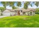 Inviting single-story home with a well-kept lawn, neutral paint, and a vibrant red front door at 206 Forest Wood Ct, Spring Hill, FL 34609