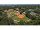 Aerial shot of well-maintained baseball fields surrounded by trees, illustrating community recreational amenities with tennis courts nearby at 2271 Carolyn Dr, Dunedin, FL 34698