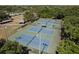 An aerial view features four well-maintained tennis courts with lighting, surrounded by trees and greenery at 2271 Carolyn Dr, Dunedin, FL 34698