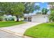 Well-maintained single-story home with green lawn, mature trees, and paved driveway at 2334 Tropical Shores Se Dr, St Petersburg, FL 33705