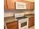 Compact kitchen includes an electric stove, microwave, wood cabinets, and neutral countertops at 240 N Bayshore Blvd # 102, Clearwater, FL 33759